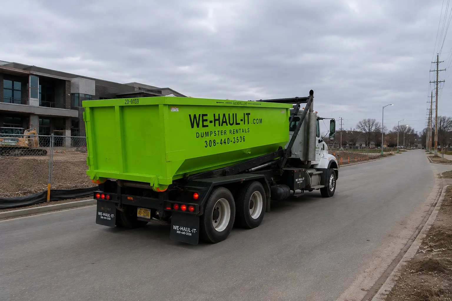 WE-HAUL-IT truck hauling away a full 15 yard roll-off dumpster after a Nebraska cleanout